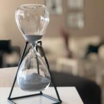 A clear glass hourglass on a white table captures the passage of time in a stylish modern interior.